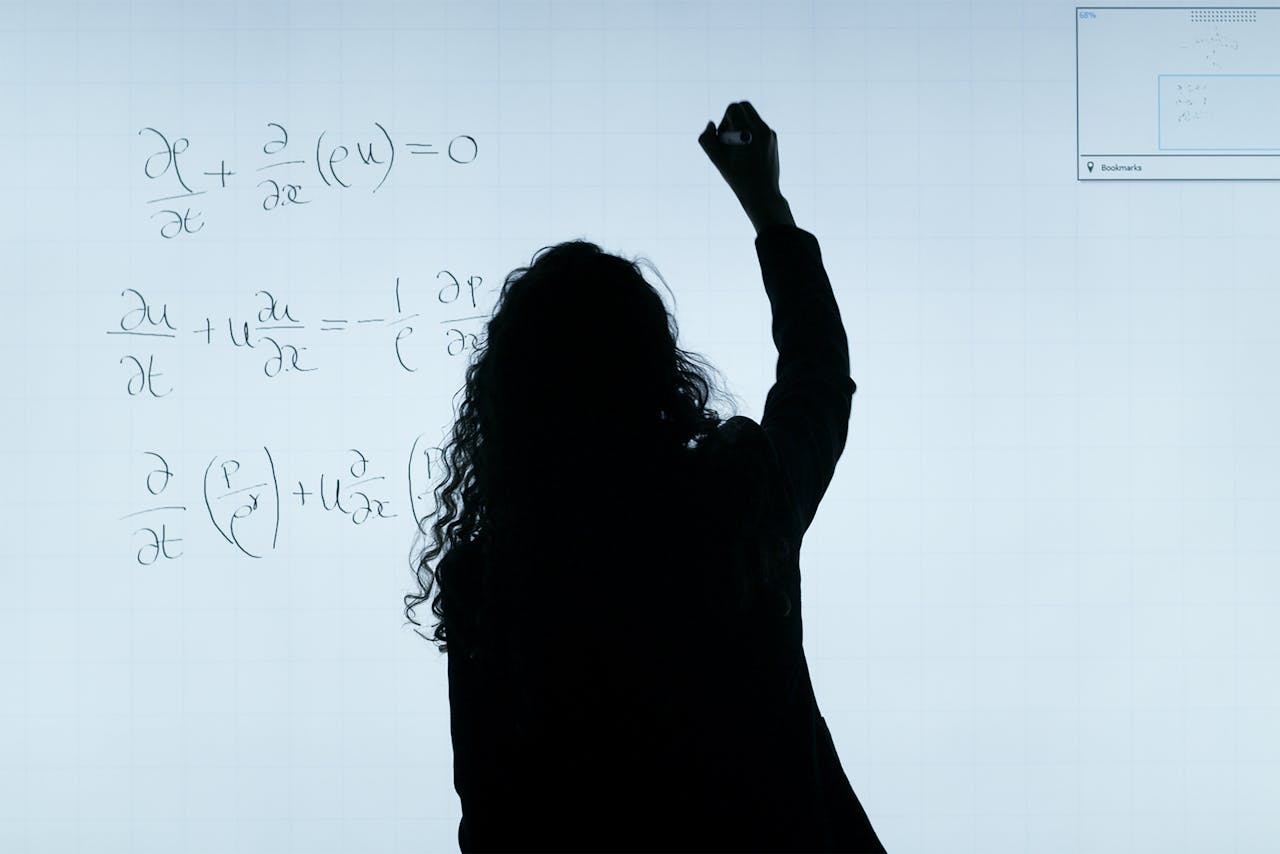 creative A silhouette of a woman writing mathematical equations on a large whiteboard, representing education and analysis.